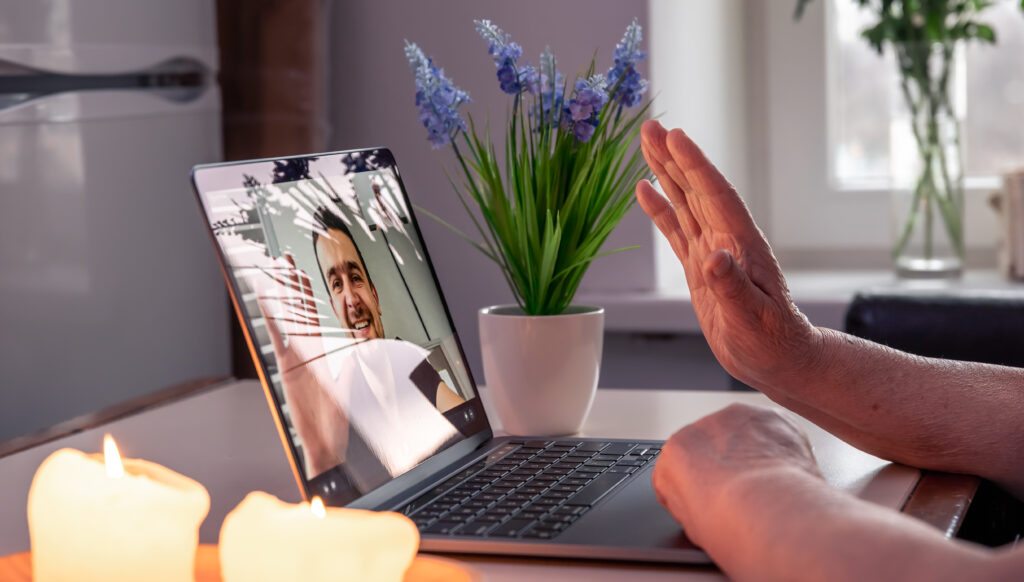 an old woman communicates with her son via video link through a laptop.